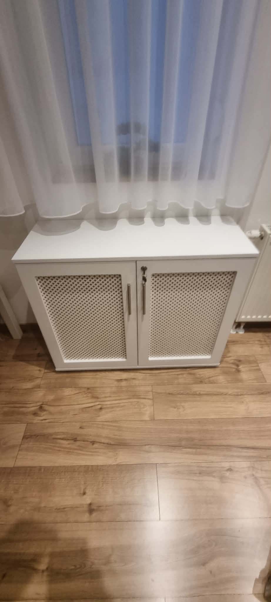 Fehér radiátorborító szekrény rácsos mintás ajtókkal